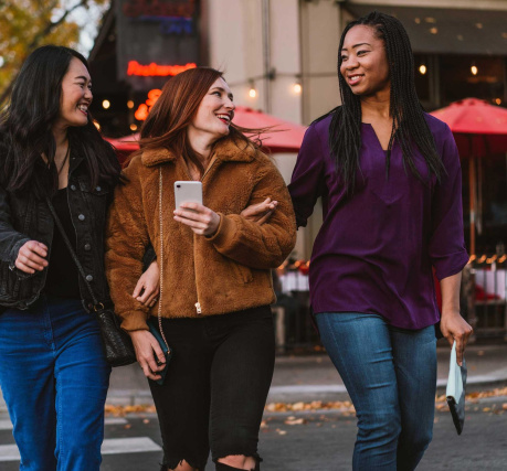 group of women walking with mobile phone in hand