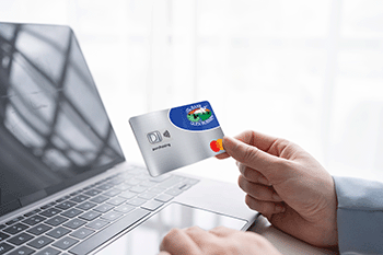 person holding BOGB Business Purchasing Credit Card and typing at computer